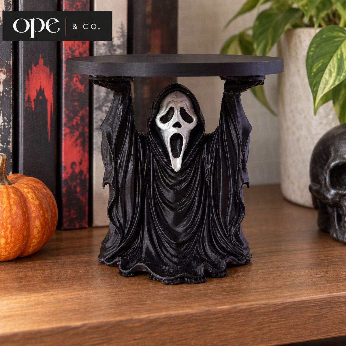 Black hooded ghost candle holder stand on a mantle with pumpkins and books