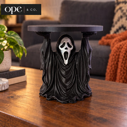 Black hooded ghost candle holder stand on a coffee table