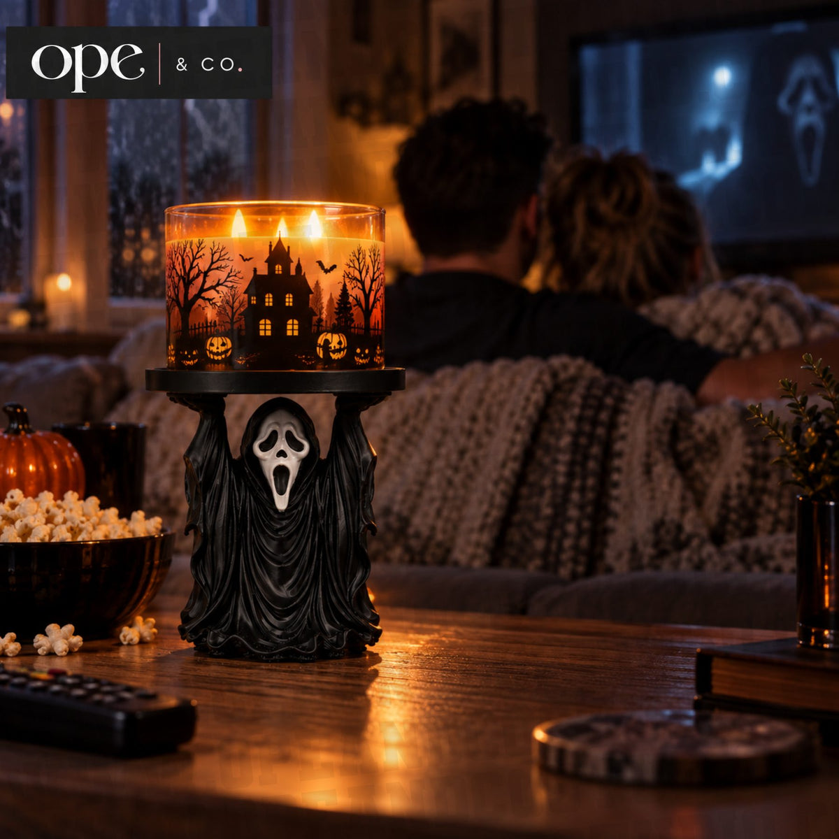 Ghost candle holder stand holding a lit three-wick candle during movie night